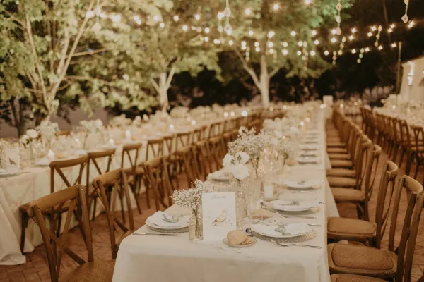 Decoración de mesas de boda con flores blancas y luces al aire libre en Cortijo Las Mozas