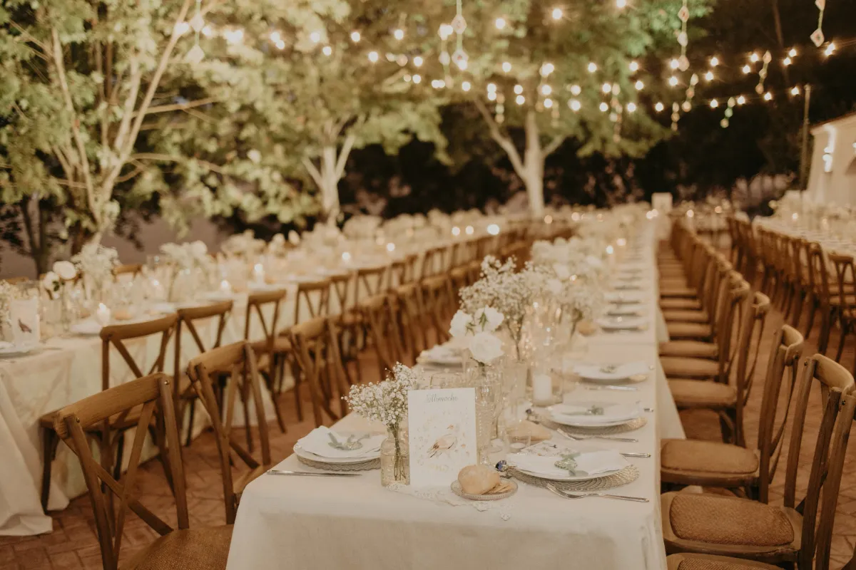 Decoración de mesas de boda con flores blancas y luces al aire libre en Cortijo Las Mozas